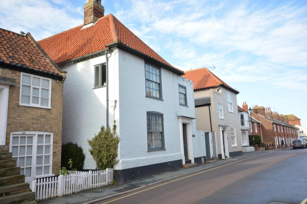 une maison blanche avec un toit rouge dans une rue dans l'établissement Gosfield Cottage, Aldeburgh, à Aldeburgh