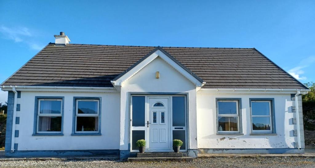 una piccola casa bianca con una porta blu di Rockgardencottage a Lettermacaward