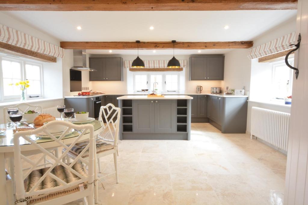 a kitchen with gray cabinets and a table with chairs at Woodland Cottage, Great Glemham in Framlingham