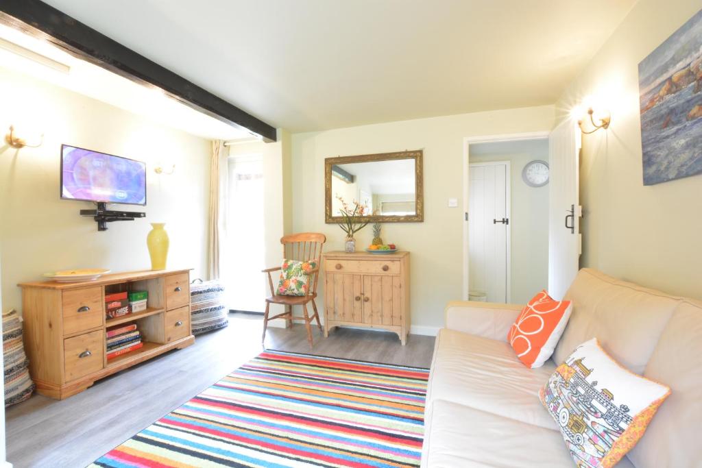 a living room with a white couch and a tv at Church Farm Cottage, Dunwich in Westleton