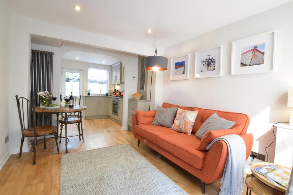 a living room with an orange couch and a table at 53 Tern Cottage, Aldeburgh in Aldeburgh