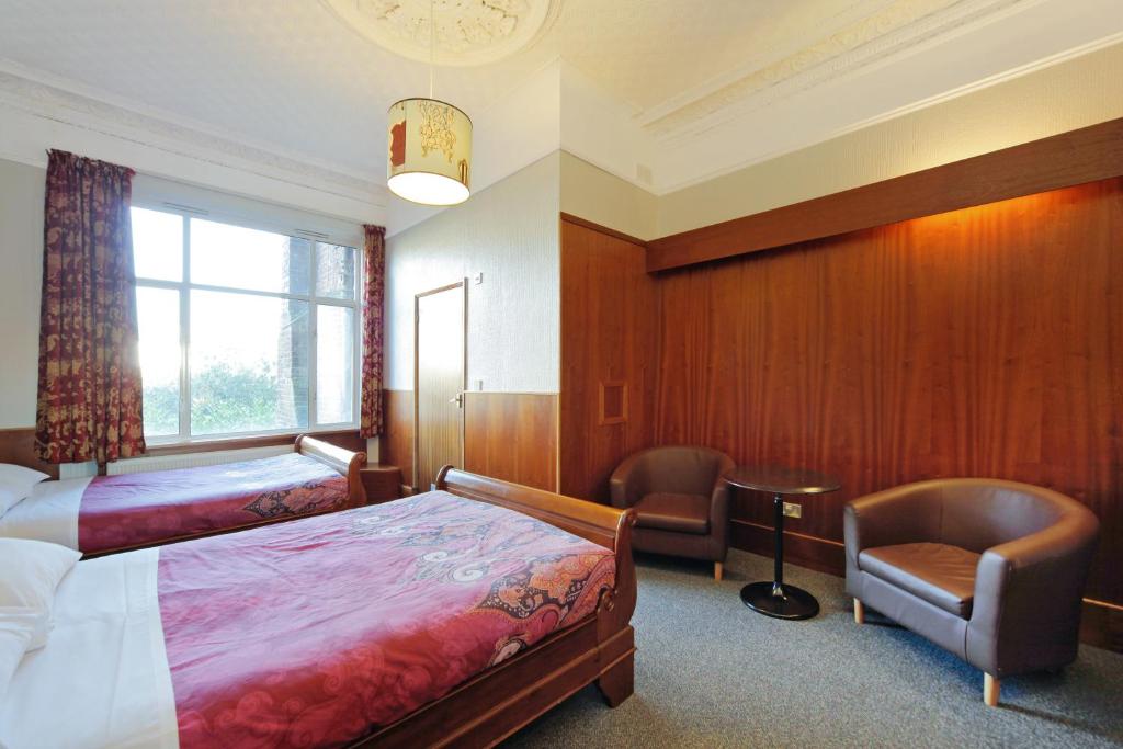 a hotel room with a bed and a chair at London Visitors Hotel in London