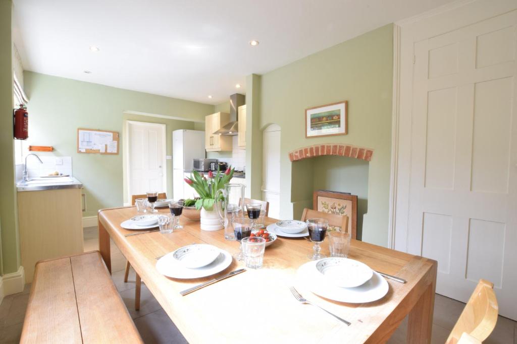 a dining room with a wooden table with plates and silverware at 14 Dunwich Road, Southwold in Southwold