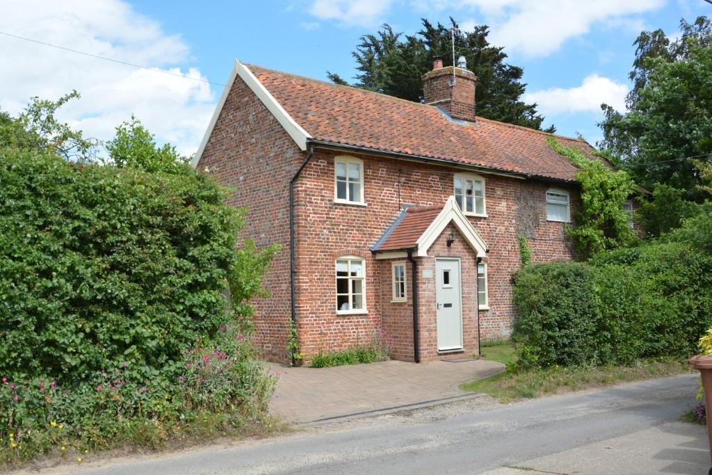 uma casa de tijolos vermelhos com uma porta branca em Shoemakers Cottage, Friston em Friston