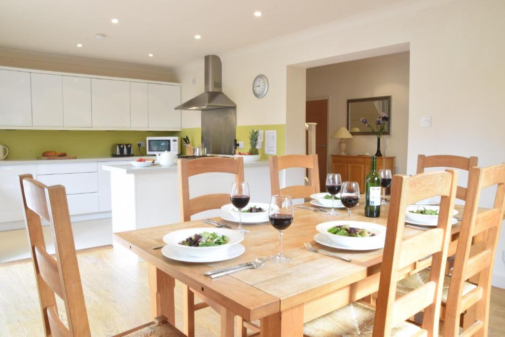 eine Küche und ein Esszimmer mit einem Holztisch mit Gläsern Wein in der Unterkunft Peach House, Aldeburgh in Aldeburgh