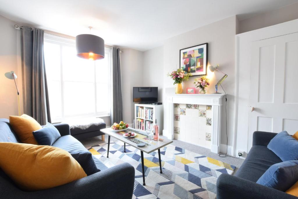 a living room with blue couches and a table at Driftwood, Southwold in Southwold