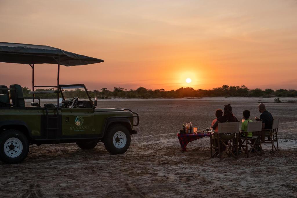 Un groupe de personnes assises à une table pour observer le coucher du soleil dans l'établissement Saadani Safari Lodge, à Saadani