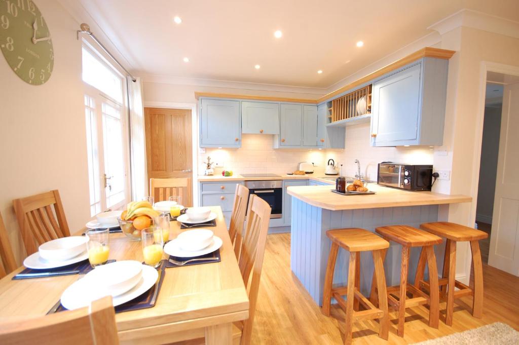 uma cozinha com armários azuis e uma mesa e cadeiras em Garden Cottage, Southwold em Southwold