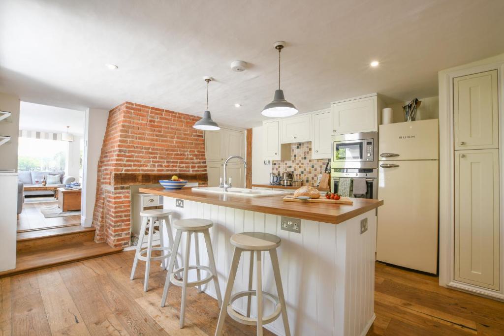 a kitchen with white cabinets and a brick wall at Beresford House in Woodbridge
