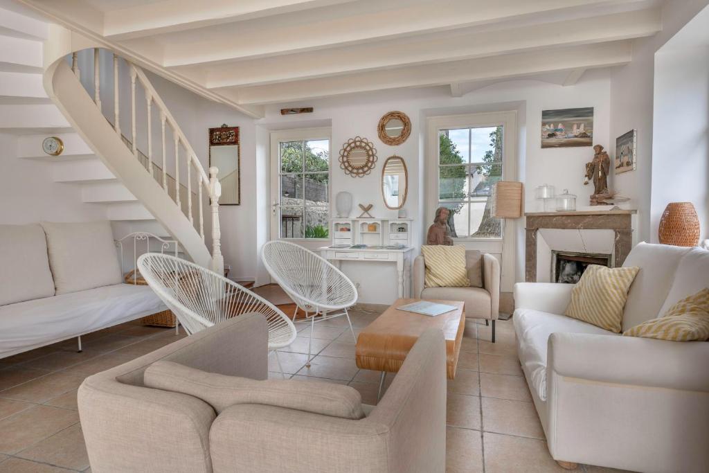 a living room with white furniture and a staircase at Maison de caractere a 100 metres de la plage in Le Pouliguen