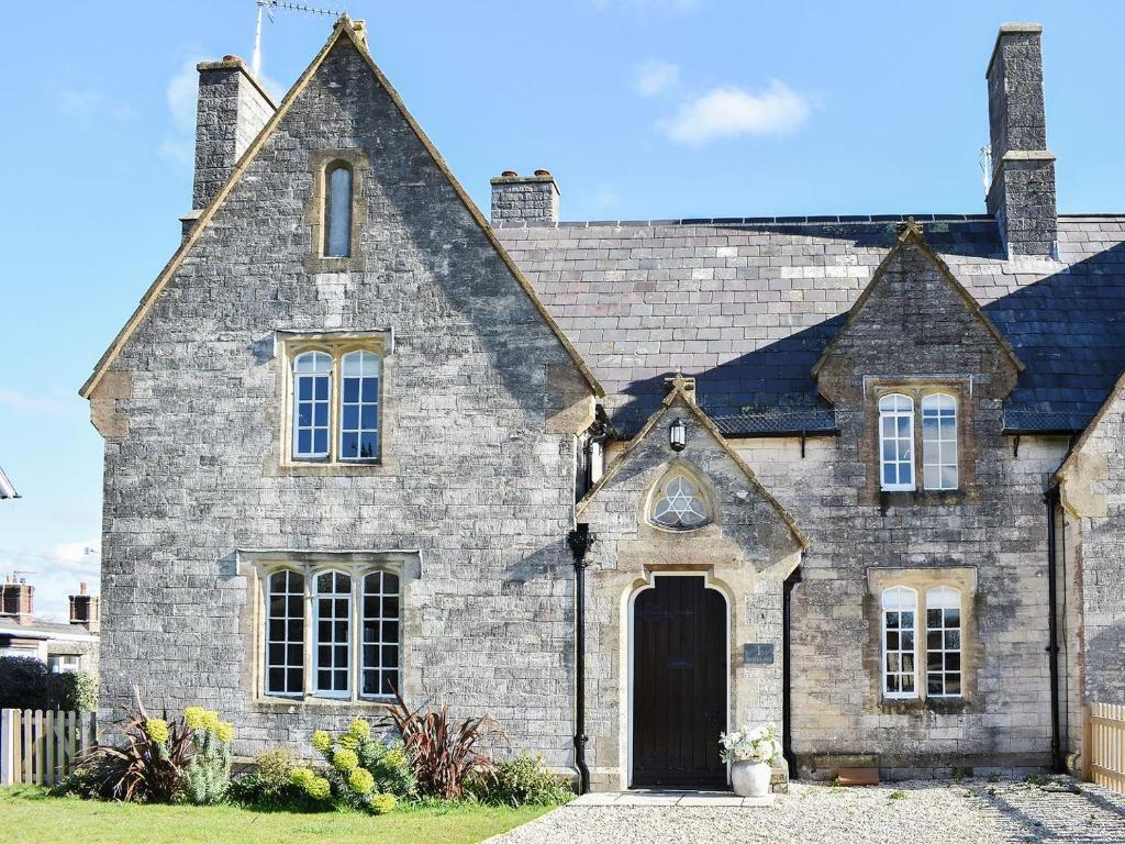 an old stone house with a black door at No, 1 The Old School in Puddletown