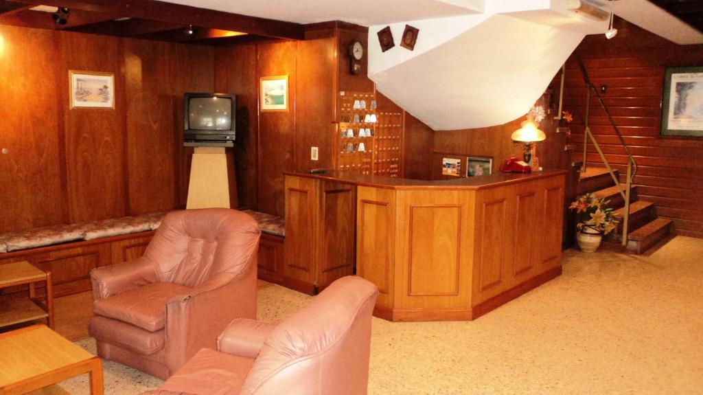 ein Wohnzimmer mit einem Sofa, Stühlen und einem TV in der Unterkunft Hotel Cielo Azul in Mar del Plata