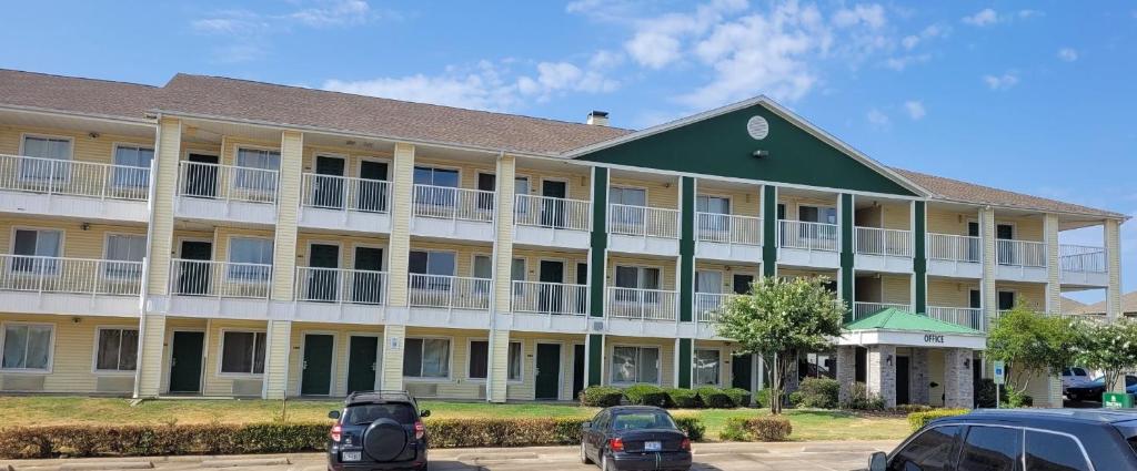 a large building with cars parked in front of it at HomeTowne Studios by Red Roof Dallas - Irving in Irving