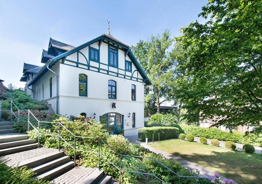 uma casa branca com um telhado azul em Das Elbcottage - Remise am Süllberg - Boarding House em Hamburgo