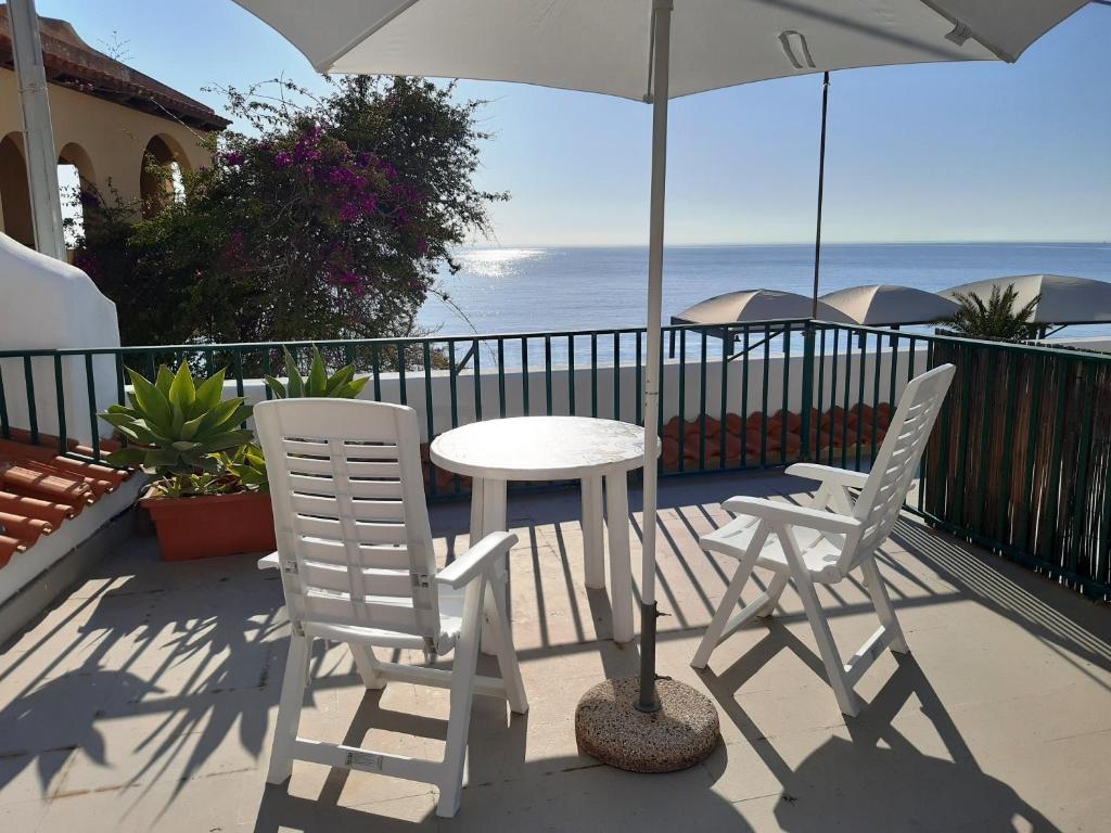 a table and two chairs and an umbrella on a balcony at Casa MARINELLA in Lipari