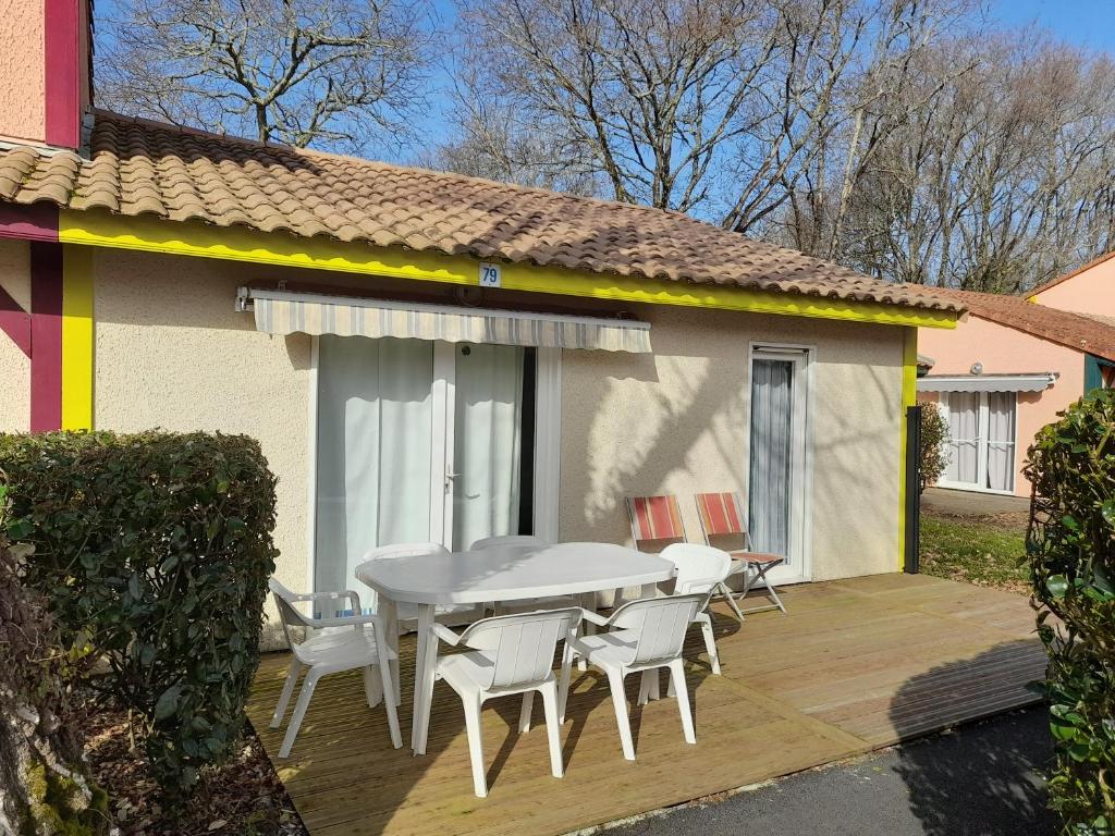 a patio with a table and chairs on a deck at Pavillon, de 4 à 7 couchages, dans une superbe résidence avec piscine in Soustons