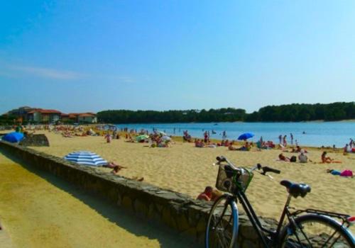 a bike parked on a beach with a bunch of people at Pavillon, de 4 à 7 couchages, dans une superbe résidence avec piscine in Soustons