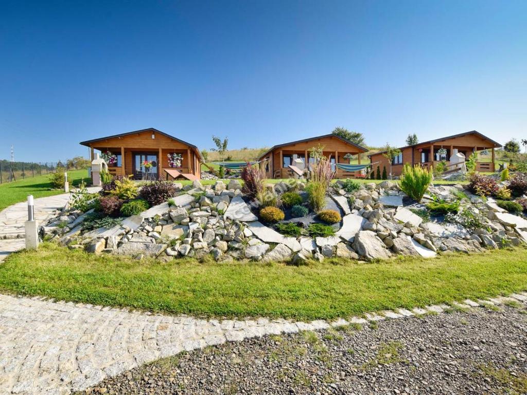 a home with a rock retaining wall and houses at Domki na Wzgórzu in Kudowa-Zdrój