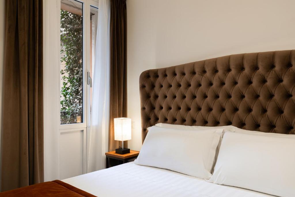 a bedroom with a bed with a large headboard and a window at Relais del Portico in Rome