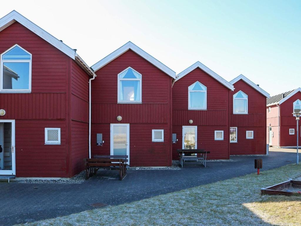 Apartment Hadsund IX في Hadsund: صف من حظائر حمراء مع مقاعد في الأمام