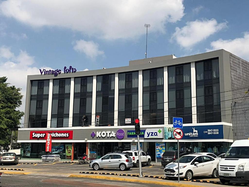 un gran edificio con coches estacionados en un estacionamiento en Vintage Lofts en Guadalajara