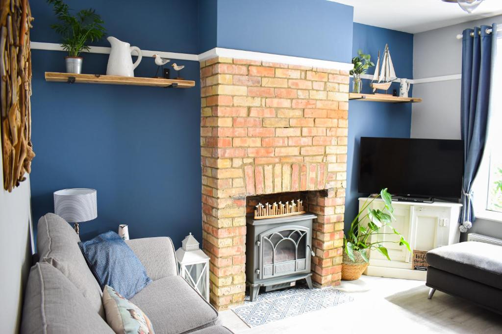 a living room with a brick fireplace and a tv at Seagull Cottage - Suffolk Coastal Escapes in Pakefield