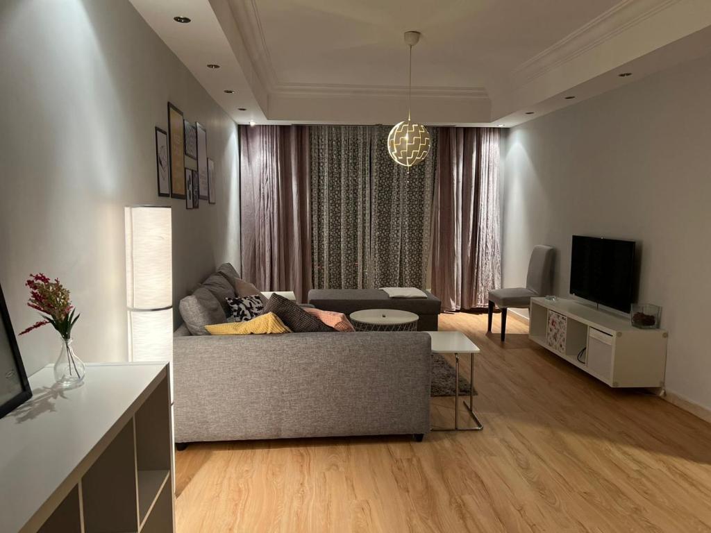 a living room with a couch and a tv at Ronza Elegant Apartment in Amman
