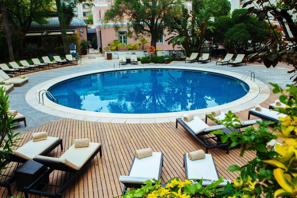 a swimming pool with lounge chairs and a table at Avani Avenida Liberdade Lisbon Hotel in Lisbon