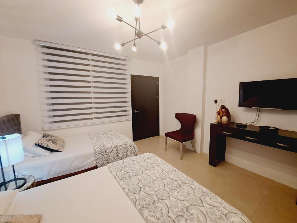 a bedroom with two beds and a desk and a television at Relax Habitación Privada in Manta