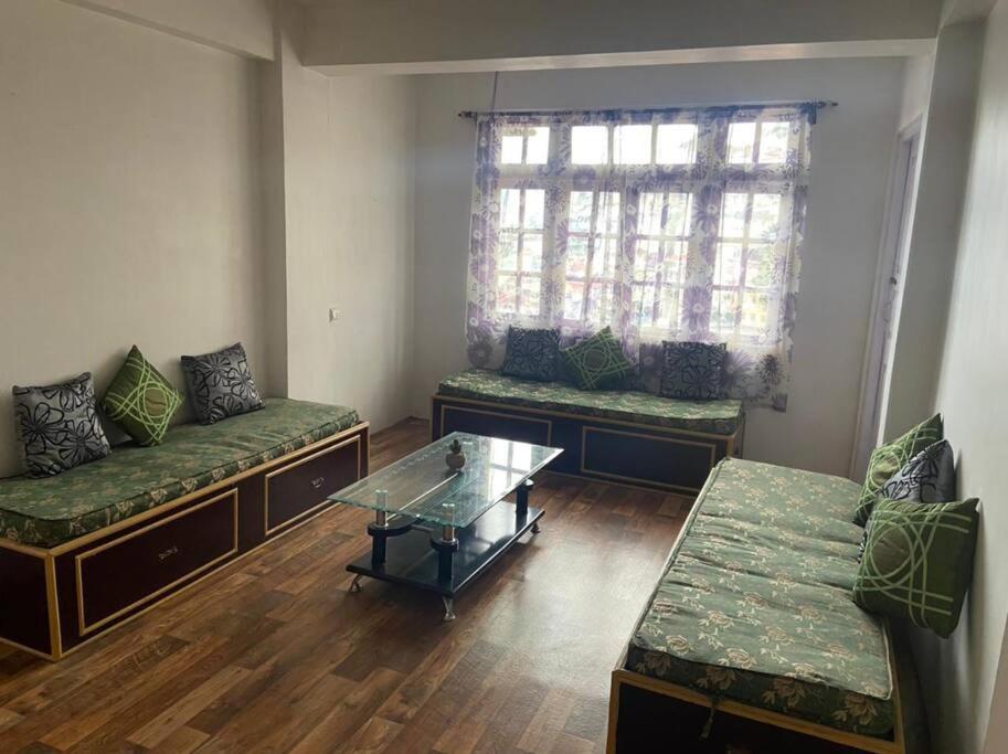 uma sala de estar com sofás e uma mesa de vidro em Norbus Homestay em Darjeeling