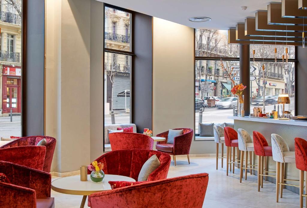 a restaurant with red chairs and tables and windows at NH Collection Marseille in Marseille