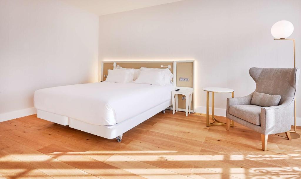 a bedroom with a white bed and a chair at NH Collection Marseille in Marseille