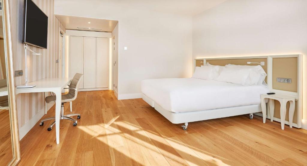 a bedroom with a white bed and a desk and a computer at NH Collection Marseille in Marseille