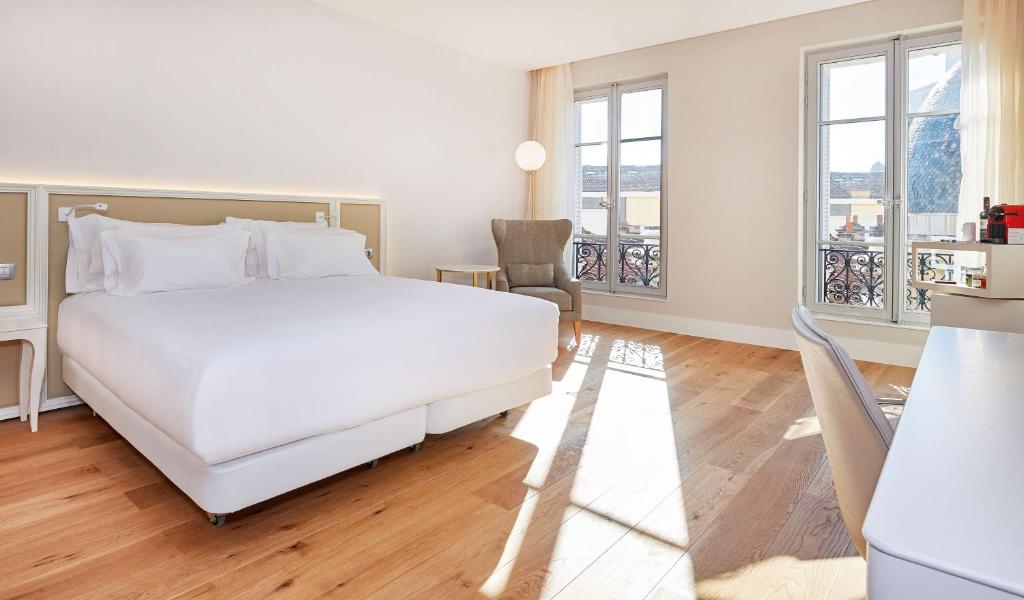 a bedroom with a large white bed and a balcony at NH Collection Marseille in Marseille