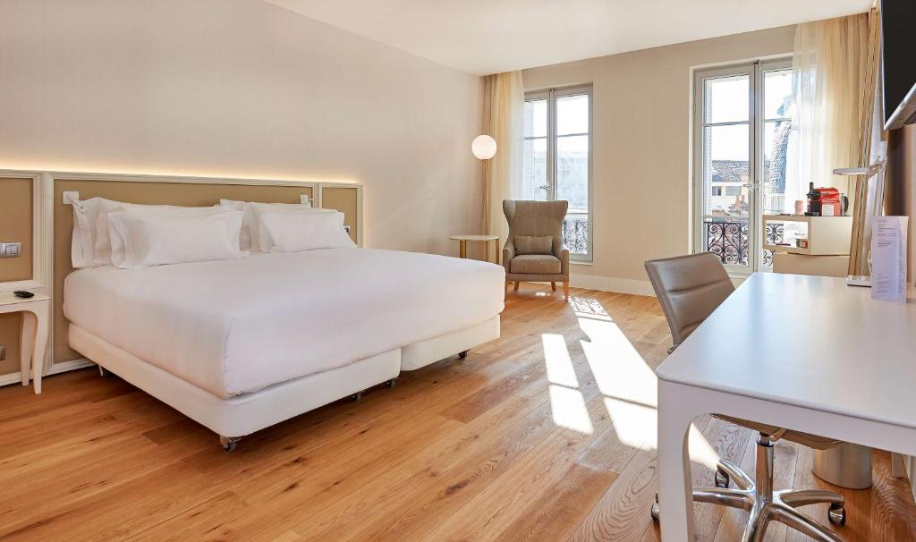 a bedroom with a large white bed and a desk at NH Collection Marseille in Marseille