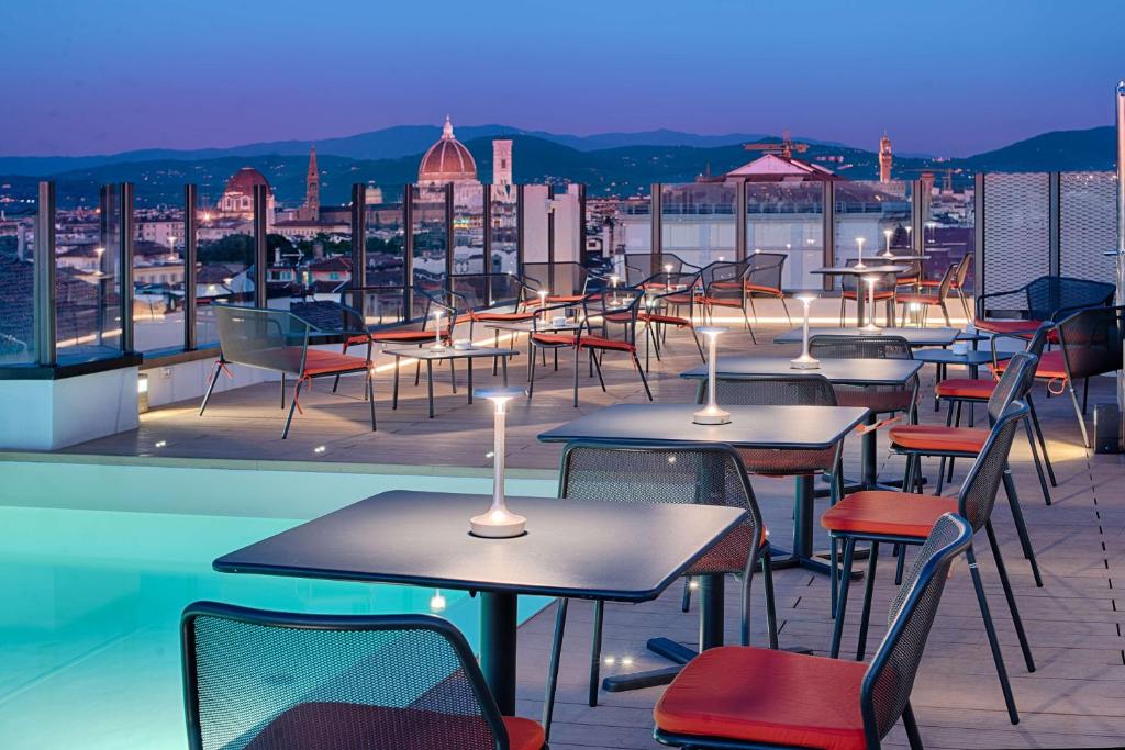 a row of tables and chairs on a roof at NH Firenze in Florence