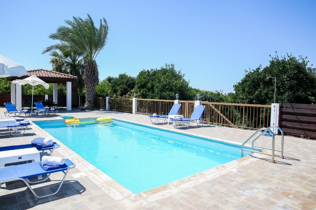 uma grande piscina com cadeiras e uma cerca em VILLA LAMBRIANA em Pegeia ou Pegya