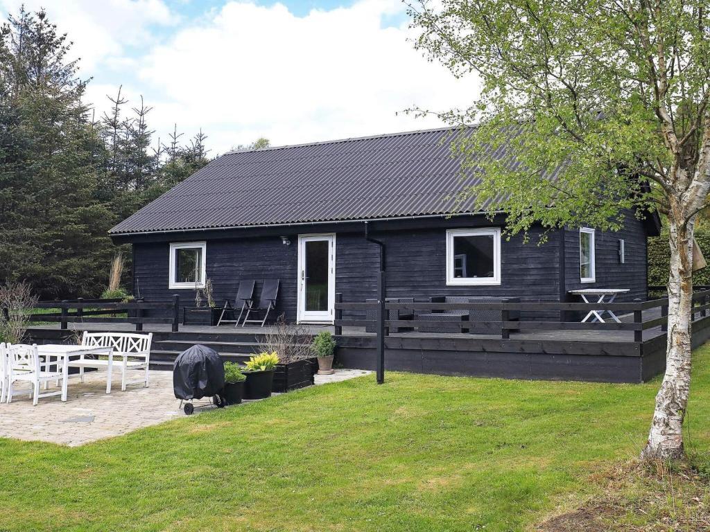 a black house with a picnic table in front of it at 6 person holiday home in Hals in Hals