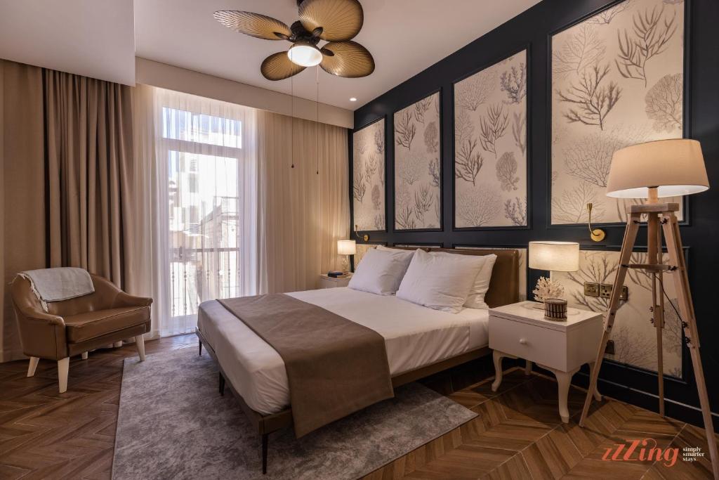 a bedroom with a bed and a chair and a window at El Doris Boutique Living in Marsaskala