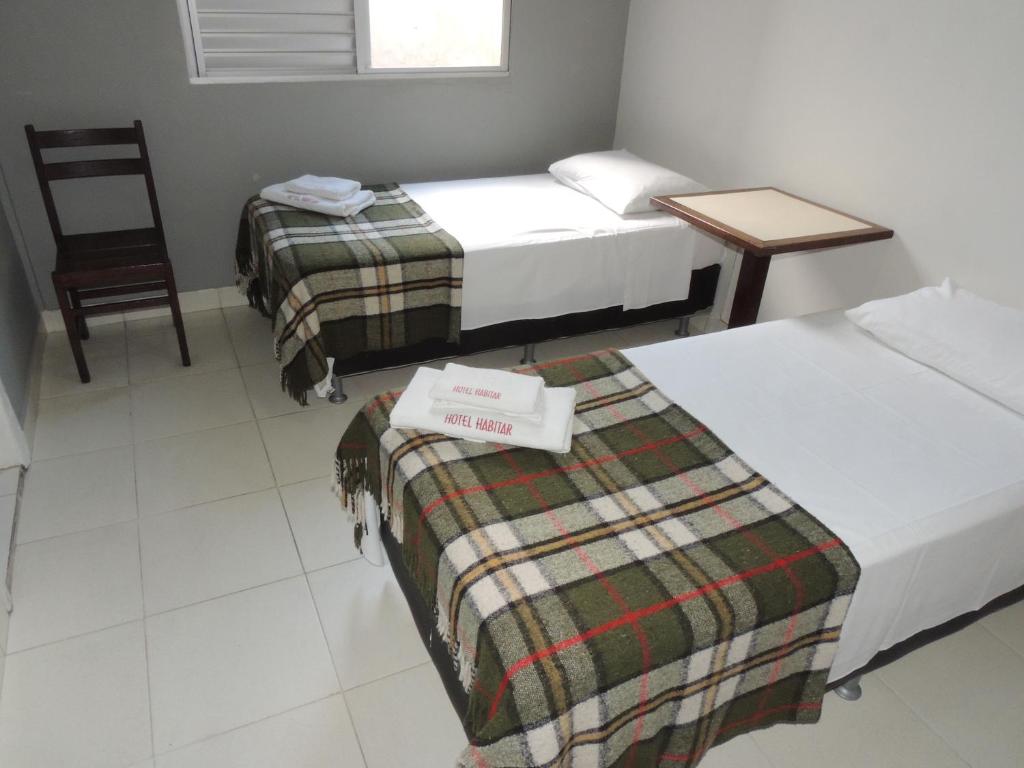 Habitación con 2 camas, silla y mesa. en Hotel Economy 888 - By UP Hotel - Próximo a Praça da Estação e Rodoviária en Belo Horizonte