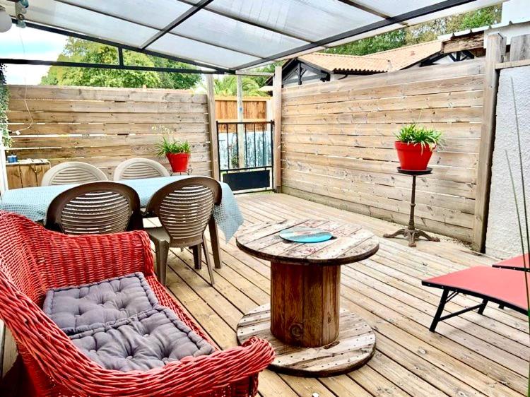 a patio with a table and chairs on a wooden deck at Maisonnette Bassin d'Arcachon in La Teste-de-Buch