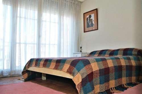 Un dormitorio con una cama con una manta. en Departamento Avenida Colon en Mar del Plata