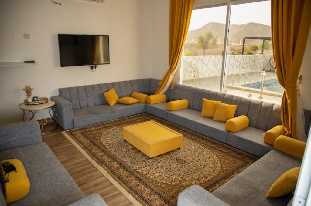 uma sala de estar com um sofá azul e almofadas amarelas em Wadi Bani Khalid - Al Joud Green Hostel em Dawwah