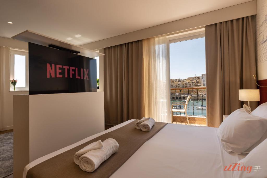 a hotel room with a television and towels on a bed at El Doris Boutique Living in Marsaskala