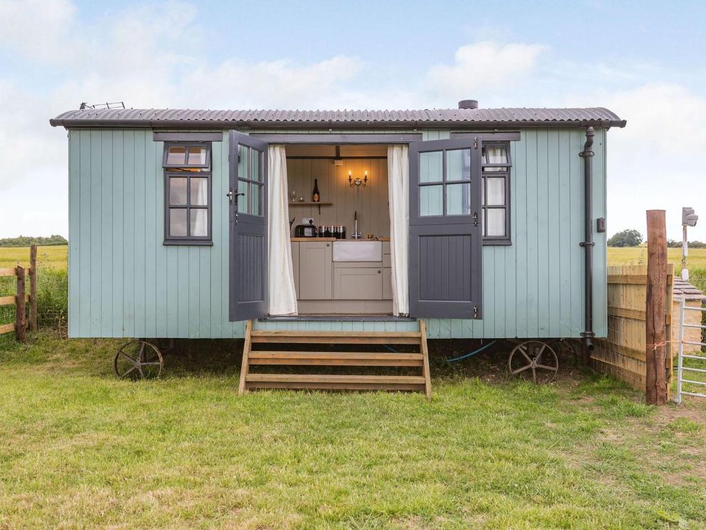 ein kleines grünes Haus mit einer Küche auf einem Feld in der Unterkunft Daisys Rest in Shipton under Wychwood