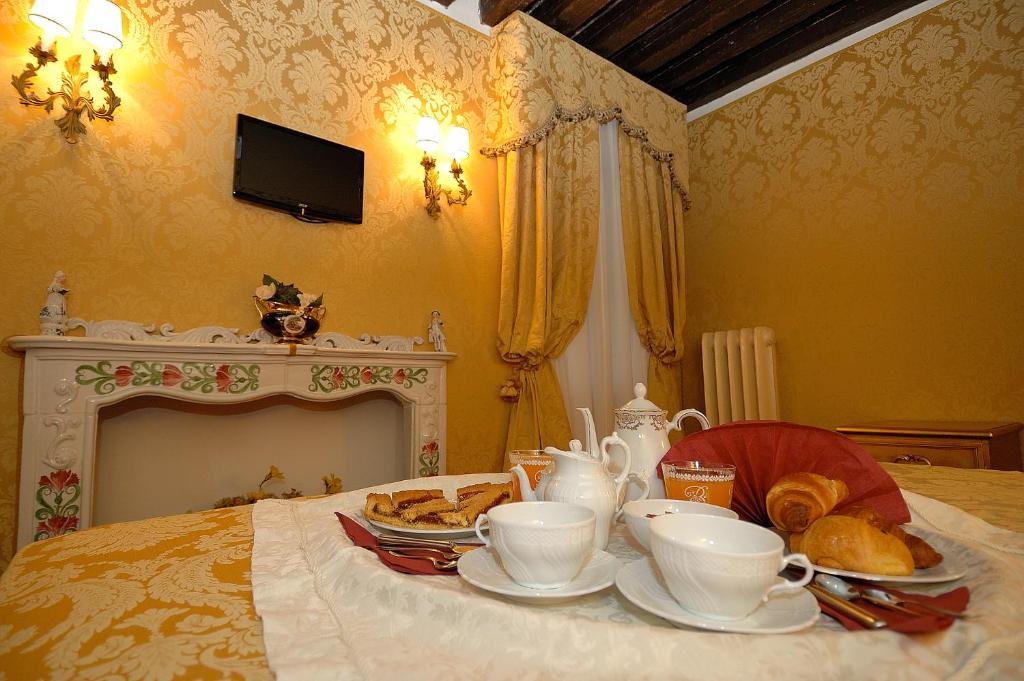 a table with cups and plates of food on a bed at Residenza La Loggia in Venice