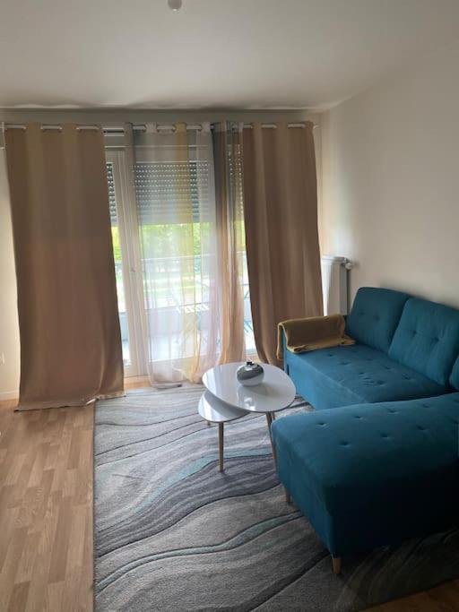 ein Wohnzimmer mit einem blauen Sofa und einem Tisch in der Unterkunft Grand appartement entier situé à aulnay-sous-bois in Aulnay-sous-Bois