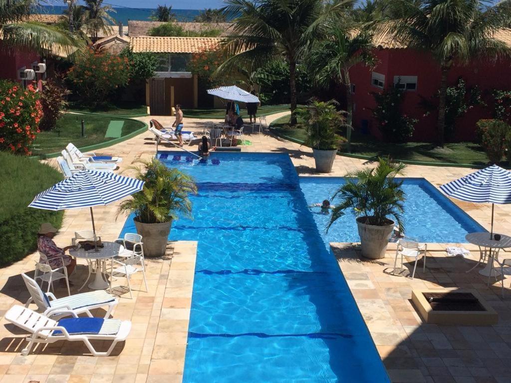 een zwembad met stoelen en parasols in een resort bij Condomínio Arituba Tropical in Nísia Floresta