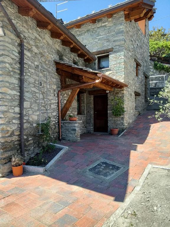 a stone building with a door and a patio at Le temps Retrouvé - casa tipica con giardino in Villeneuve
