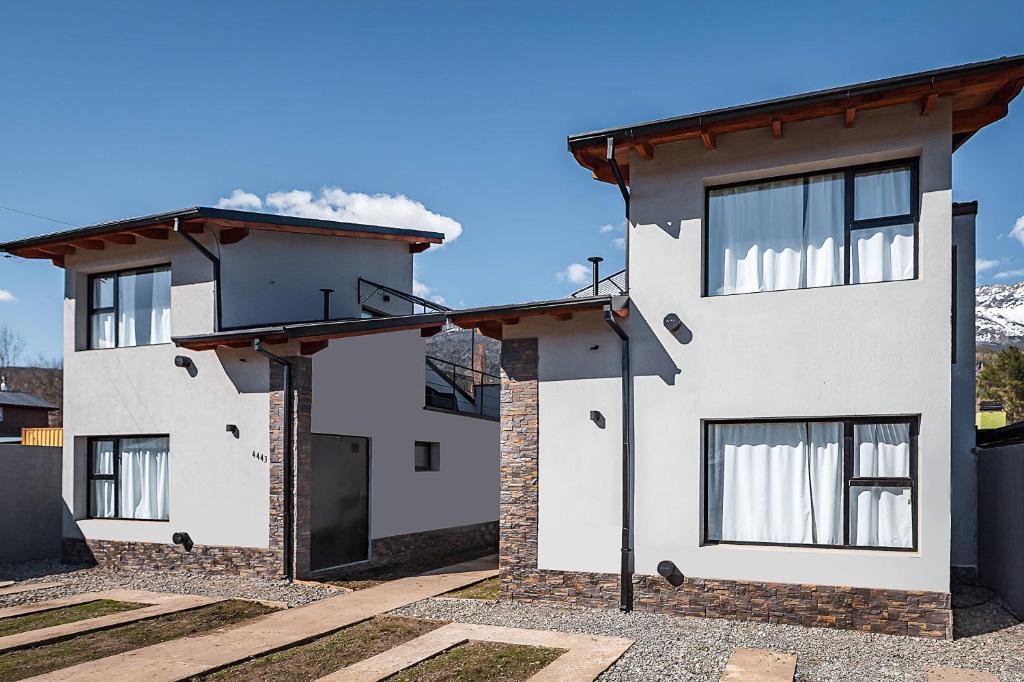 Biały dom z oknami i niebieskim niebem w obiekcie Cabañas El Aby w mieście El Bolsón